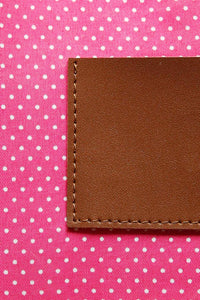 Pink with white polka dot cotton lining on a brown leather clutch