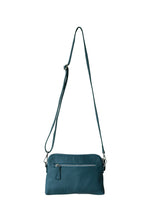 Load image into Gallery viewer, Back view of a teal leather crossbody bag. With fully adjustable strap and silver zips, Hoopla brand. 