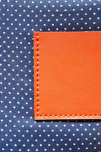 Load image into Gallery viewer, Navy with white polka dot cotton lining on an orange leather clutch