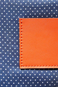 Navy with white polka dot cotton lining on an orange leather clutch